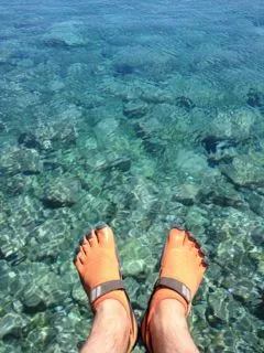 Two feet stretched out over clear blue water